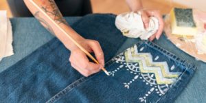 Close-up of woman customizing jeans at OM Clothing